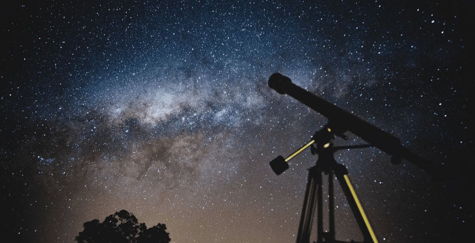 a telescope points to a dark starry sky