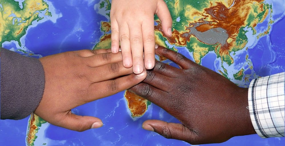 three hands covering the continent of Africa on a map