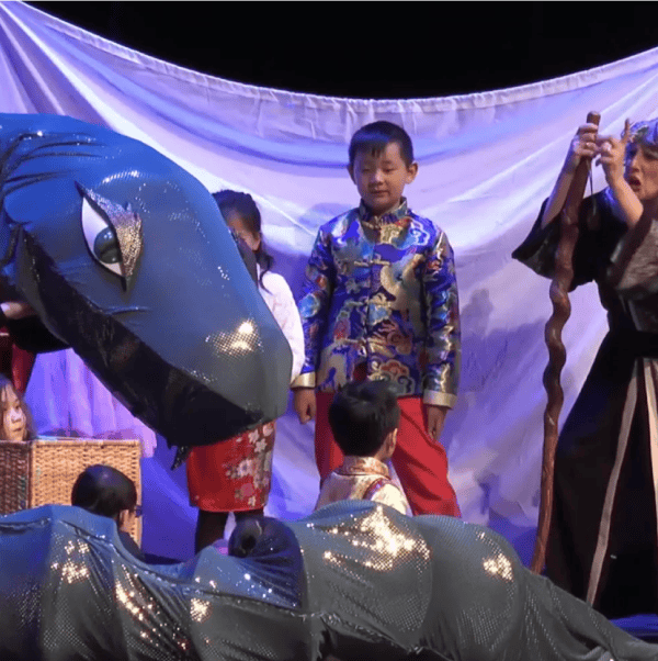 a young boy looks towards a large grey, shiny snake